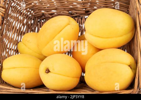 Plusieurs abricots jaune vif juteux d'ananas sur une serviette jute, macro isolée sur un fond blanc. Banque D'Images