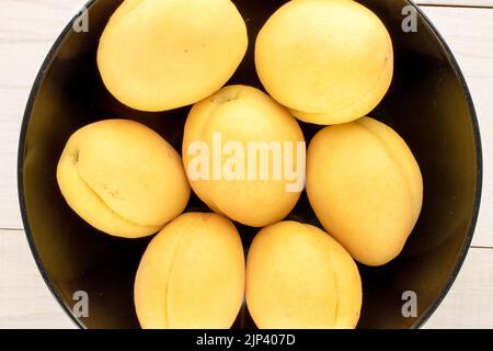 Plusieurs abricots jaune vif juteux d'ananas dans une plaque en céramique sur une table en bois, macro, vue de dessus. Banque D'Images