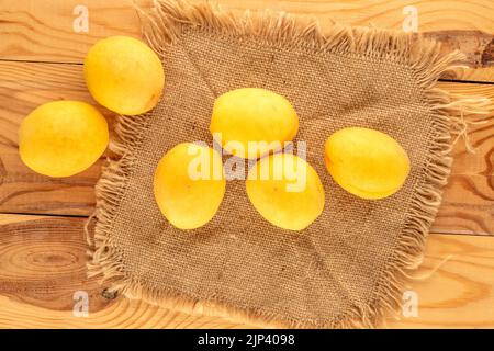 Plusieurs abricots jaune vif juteux d'ananas sur une serviette jute, macro, vue de dessus. Banque D'Images