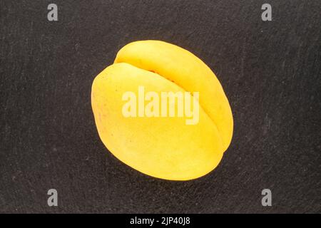 Un abricot jaune vif juteux d'ananas sur une pierre d'ardoise, macro, vue de dessus. Banque D'Images