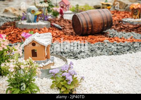 Aménagement de jardin avec des billes de bois, paniers en osier, gravier et divers ornements Banque D'Images