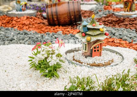 Aménagement de jardin avec des billes de bois, paniers en osier, gravier et divers ornements Banque D'Images