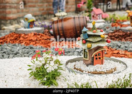 Aménagement de jardin avec des billes de bois, paniers en osier, gravier et divers ornements Banque D'Images