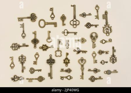 Différentes tailles et types de clés ornementales en bronze pour les horloges et les caisses de Trésor en organisant à 90 degrés les uns des autres sur fond de papier rose Banque D'Images