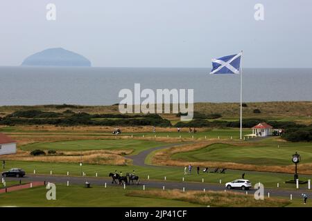 Trump Turnberry, Ayrshire, Écosse Royaume-Uni..l'un des plus grands drapeaux de la saltire en Écosse domine la région et peut être vu de miles autour. Cette vue vue vue de l'hôtel Turnberry avec la hutte d'entrée pour le premier tee, les greens d'entraînement et le vert 18th. Sur la photo se trouve également la grande horloge emblématique qui porte le nom de Donald Trump. Les golfeurs s'exercent sur les greens, avec un peu de teeing du tee de 1st. Les cavaliers passent à l'horizon est le Firth of Clyde sur la côte ouest de l'Écosse avec la forme emblématique d'Ailsa Craig Banque D'Images