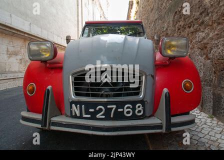 Un gros plan du bouclier rouge Citroën 2 cv stationné dans une rue étroite à Lisbonne, Portugal Banque D'Images