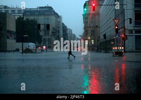 Berlin, Allemagne. 15th août 2022. Un homme marche à travers une intersection dans la pluie lourde crédit: Carsten Koall/dpa/Alamy Live News Banque D'Images