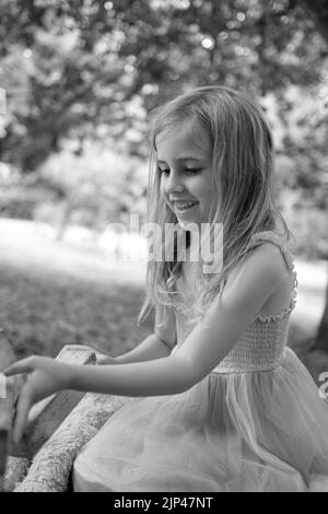 5yr vieille fille en robe rose et bleue jouant avec des blocs de bois dans un cadre de parc Banque D'Images