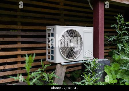 Nouvelle unité de compresseur externe de climatisation HVAC moderne préinstallée pour installation ou remplacement près du mur de chalet résidentiel en bois Banque D'Images