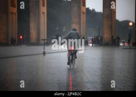 Berlin, Allemagne. 15th août 2022. Un homme traverse la place Pariser en vélo sous une forte pluie. Credit: Carsten Koall/dpa/Alay Live News Banque D'Images