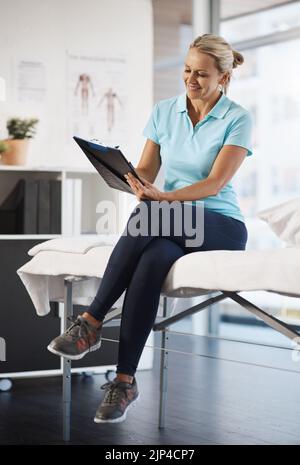 Mise à jour de ses enregistrements. Prise de vue en longueur d'une femme kinésithérapeute mature travaillant dans son bureau. Banque D'Images