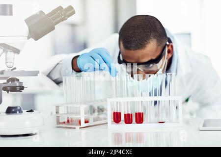 Un scientifique intelligent travaillant dans un laboratoire avec des échantillons de sang, des tests d'ADN ou des recherches sur les virus. Tube à essai d'analyse d'expert en sciences ou en biologie de sexe masculin noir Banque D'Images