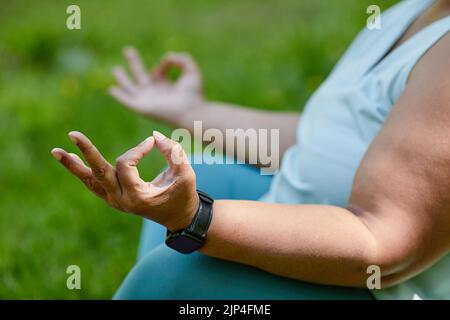 Gros plan d'une femme en surpoids méconnaissable faisant du yoga à l'extérieur et méditant en se concentrant sur les mains, l'espace de copie Banque D'Images