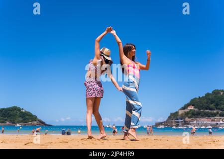 Une belle photo de deux sœurs qui s'amusent pendant leurs vacances et dansent à la plage Banque D'Images