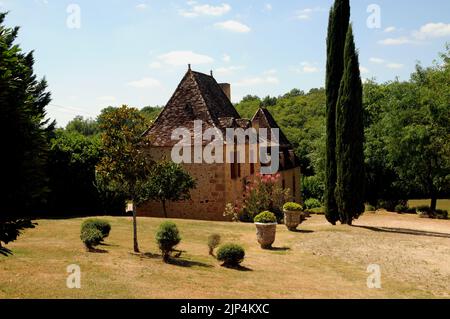 Un bel exemple de maison de campagne dans la région du Périgord Noir de la Dordogne. Il est construit en pierre de couleur miel avec un toit fortement incliné. Banque D'Images