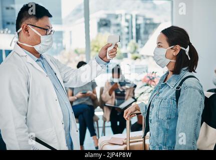 Covid voyageant avec un médecin prenant la température d'une femme portant un masque dans un aéroport pour la sécurité en cas de pandémie. Professionnel de la santé avec un Banque D'Images