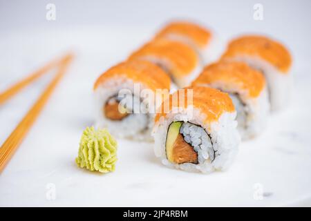 Petits pains à sushis sur plateau, fond lumineux. Servi avec du wasabi et du gingembre. Assortiment de sushis japonais. Cuisine traditionnelle. Banque D'Images