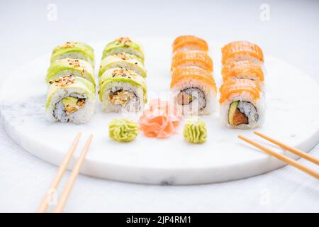 Petits pains à sushis sur plateau, fond lumineux. Servi avec du wasabi et du gingembre. Assortiment de sushis japonais. Cuisine traditionnelle. Banque D'Images
