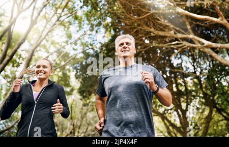 Sport, actif et sain couple mature jogging, courir et profiter de leur style de vie en plein air dans la nature pendant l'été. Heureux, souriant et gratuit Banque D'Images