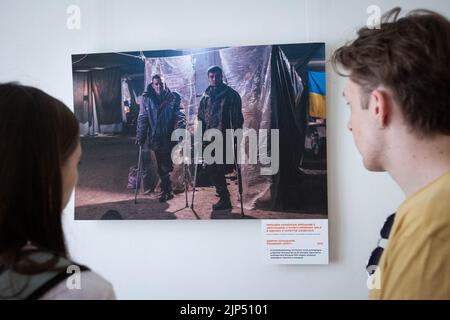 Kiev, Ukraine. 14th août 2022. Les gens regardent des photos du soldat-photographe d'Azov Dmytro 'Orest' Kozatsky présentées à l'exposition intitulée 'sans précédent Azovstal' à Kiev. Les photographies de Dmytro 'Orest' Kozatsky montrent les réalités des soldats du régiment d'Azov assiégés à l'usine d'acier d'Azovstal à Marioupol. Avant d'être capturé Kozatsky a publié ses photos sur les réseaux sociaux afin des diffuser aussi largement que possible. Crédit : SOPA Images Limited/Alamy Live News Banque D'Images