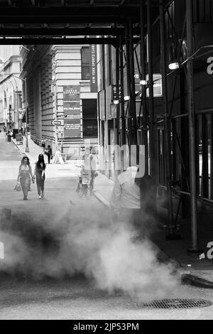 Une photo verticale en niveaux de gris d'une rue de Manhattan avec des gens passant par une zone fumée Banque D'Images