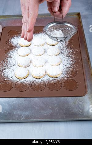 Confiseur saupoudrer le sucre sur des friandises de mariage sur une plaque de silicone brune vertical. Banque D'Images