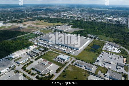Une vue aérienne haute qui regarde un grand entrepôt avec des remorques de tracteur arrimées autour du bâtiment. Vue dans une vaste zone industrielle par temps ensoleillé. Banque D'Images