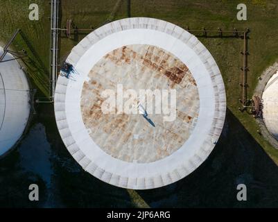 Vue aérienne directe au-dessus d'un réservoir de stockage de pétrole brut blanc par temps ensoleillé. Banque D'Images