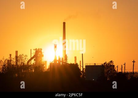 Le soleil du soir brille un fumoir industriel, grande usine au crépuscule. Banque D'Images