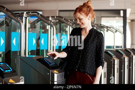 Une femme qui scanne un téléphone pour entrer dans un bâtiment moderne ou qui sécurise une entreprise à l'aide d'un lecteur sensoriel sans contact ou d'une machine. Une femme tendance Banque D'Images