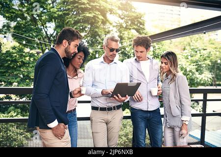 Faisons un peu plus de recherches à ce sujet. Un groupe d'hommes d'affaires travaillant ensemble sur un ordinateur portable à l'extérieur. Banque D'Images