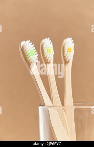 Ensemble de trois brosses à dents écologiques en bambou dans une tasse en verre. Concepts : mode de vie durable, utilisation de matériaux compostables et respectueux de l'environnement Banque D'Images