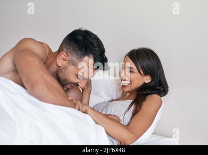 Mon propre réveil personnel. Un jeune couple affectueux et marié au lit à la maison. Banque D'Images