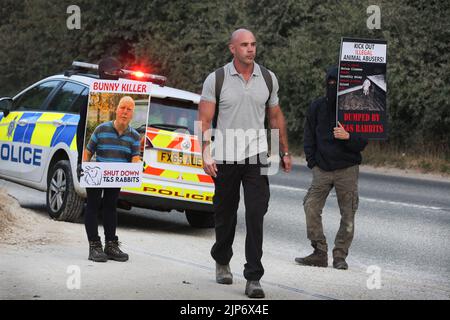 Ancaster, Royaume-Uni. 15th août 2022. Un travailleur passe devant la police et les militants des droits des animaux pendant la manifestation. Les militants des droits des animaux exercent une forte pression sur Phil Kerry pour qu'il ferme les lapins T&S à East Bridgford. Ils soutiennent qu'il traite les lapins très mal sur sa ferme, en les négligeant et en les utilisant pour la fourrure et la viande. Ils exigent que les lapins T&S se ferment et tous les lapins sont libérés. Crédit : SOPA Images Limited/Alamy Live News Banque D'Images