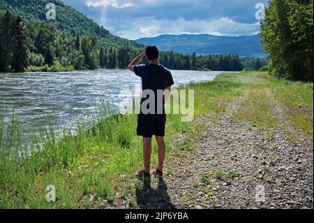 Vue arrière de l'homme mûr debout sur la rive de la rivière Banque D'Images