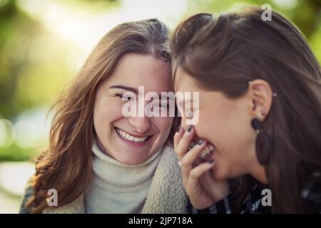 C'est tout amusant et jeux quand theyre ensemble. Deux jeunes femmes attrayantes rient en s'asseyant dans le parc. Banque D'Images