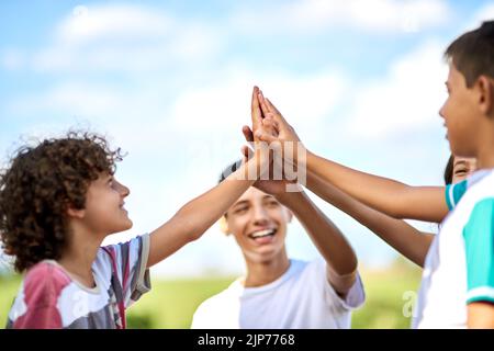 Vous pouvez toujours compter sur les frères et sœurs pour vous garder motivé. Un groupe de frères et sœurs heureux se donnant un haut cinq dehors. Banque D'Images