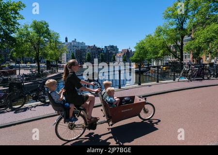 Amsterdam, pays-Bas - 22 juin 2022 : mère avec enfants à vélo sur Ir. B. Pont Bijvoetbrug Banque D'Images