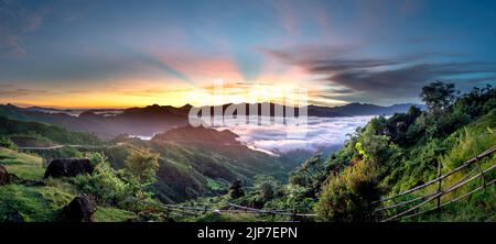 Vue panoramique sur le lever du soleil avec un sentier traversant une vallée remplie de nuages blancs dans les montagnes Tak po dans la commune de Tra Tap, dans le district de Nam Tra My Banque D'Images