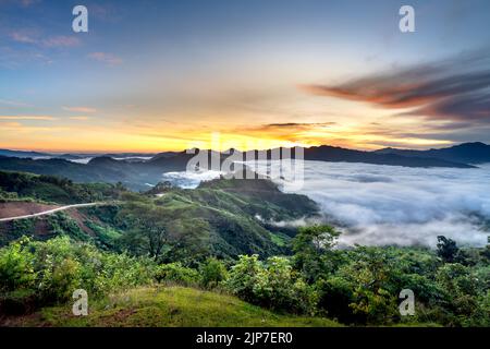 Vue panoramique sur le lever du soleil avec un sentier traversant une vallée remplie de nuages blancs dans les montagnes Tak po dans la commune de Tra Tap, dans le district de Nam Tra My Banque D'Images