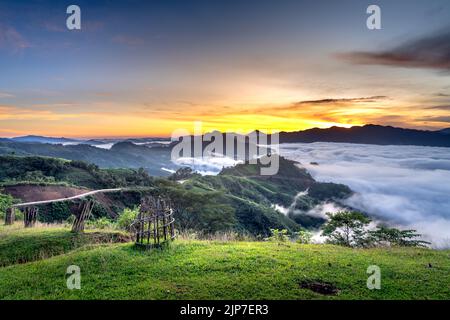 Vue panoramique sur le lever du soleil avec un sentier traversant une vallée remplie de nuages blancs dans les montagnes Tak po dans la commune de Tra Tap, dans le district de Nam Tra My Banque D'Images