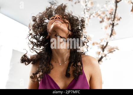 Photo avec mouvement d'une femme avec des cheveux bouclés agitant les cheveux dans un salon de beauté Banque D'Images