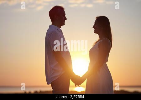 Les stands de couple montrent l'amour pur les uns envers les autres au coucher du soleil Banque D'Images