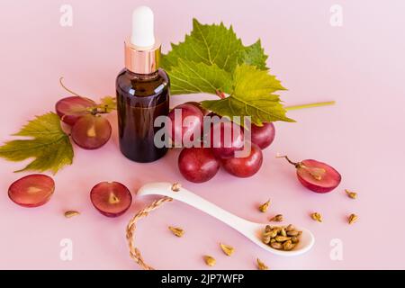 bouteille cosmétique avec distributeur en verre foncé avec huile biologique ou lactosérum à base de graines de raisin. soins de la peau supplémentaires, nutrition. fond rose Banque D'Images