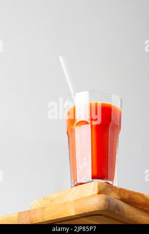 Vue de dessous du jus de tomate fraîchement pressé fait maison avec une paille de verre en gros plan Banque D'Images