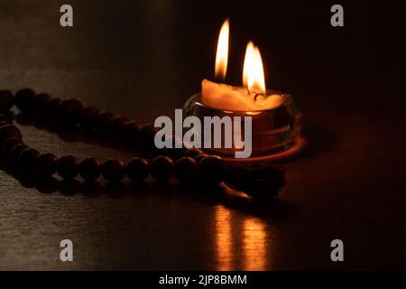 Bougies dans un chandelier sur une table près d'un rossary en bois, foi et religion, feu de bougie Banque D'Images