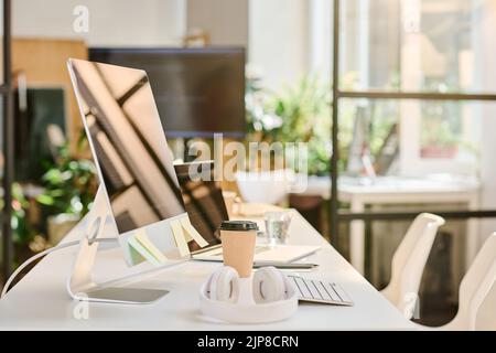 Image horizontale du lieu de travail du programmeur au bureau avec ordinateur, casque et boisson à base de café Banque D'Images