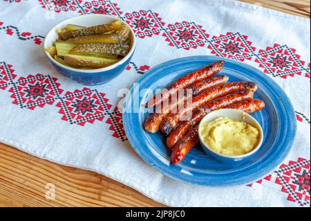 délicieux plat avec des saucisses grillées, des concombres marinés et de la moutarde Banque D'Images