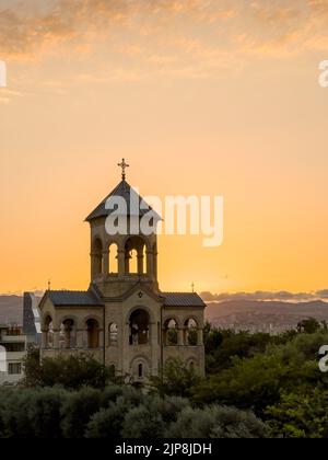 Tard dans la soirée, un coucher de soleil lumineux illumine le soleil à travers les petites arches de la chapelle près de la cathédrale Sainte-Trinité de Tbilissi, en Géorgie. Banque D'Images