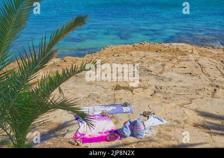 Portugal serviette de plage avec chapeau, lunettes de soleil et tongs sur sable naturiste Banque D'Images